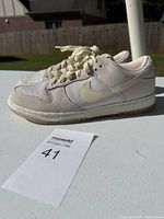 Side view of the left shoe showing the Nike swoosh and shoe color details on an outdoor white table