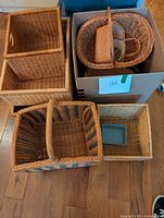 Photo showing a group of baskets: a large rectangular basket, a medium rectangular basket, and smaller square and rectangular baskets with woven textures and handles.