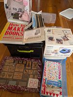 Full view of bookbinding kit, book How to Make Books, stamp blocks, inks, and sticker maker box with decorating items.