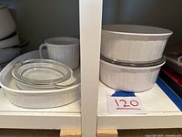 Shelved Corning Ware bakeware including oval and round dishes with lids