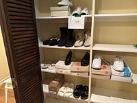 Photo showing various women's shoes on white shelving, including boots, sandals, and sneakers, mostly new or lightly used.