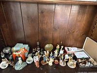 Wide view of the collection showing different figurines including animals, angels, and decorative items on wooden shelf