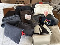 Multiple travel bags and accessories including pouches, sleep masks, and canvas tote with red print.