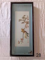 Full view of hand-carved shell birds and leaves enclosed in a vertical dark wood shadow box frame with blue matte background. Shows overall item condition and design.