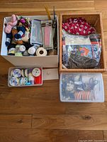 Overview of four containers holding yarn, fabric, ribbons, and crafting supplies on a wooden floor.