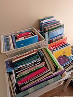Wide view of several plastic bins filled with assorted notebooks, journals, and graph paper books in various sizes and colors.