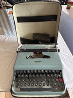 Olivetti typewriter opened inside the carrying case showing keyboard and carriage.