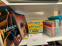 Shelf display of origami books, fold-a-day calendars, and origami paper, showing titles and colorful packaging.