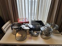 Full display of all pots and pans including pressure cooker, roaster, steamed stacked pots, and bamboo steamer boxed set.