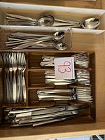 Top view of trays holding multiple forks, spoons, long spoons, and knives arranged neatly.