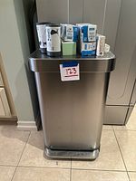 Front view of the rectangular Simple Human trash can with multiple boxes and rolls of trash bags placed on top.