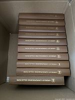 Ten brown "American Commemorative Collections" binders in storage box