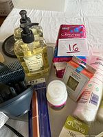 Close-up photo of liquid soap bottles, nail polish remover, cotton pads, and feminine hygiene pads for detail verification of items.