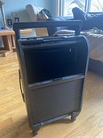 Front and top view of black plastic carry-on suitcase with ridged bottom section and smooth top section, retractable handle extended.