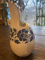 Side view of the ceramic vase showing the hand-painted blue floral design and gold accent on the spout edge