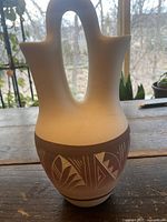 Front view of white and brown ceramic wedding vase with intricate Southwest-style engraved and painted designs on the brown band near the base, showing double spout and side handles