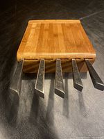 Top side view of bamboo cutting utensil block showing the backs of 5 knife handles inserted in slots.