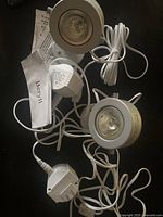 Two white round spotlight fixtures with cables and plug adapter visible on a dark surface, including instruction booklet labeled 'Beryll'.