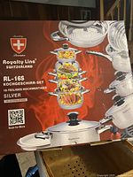 Image of the Royalty Line cookware set box showing stacked pots with cooked food illustration, brand logo, product line RL-16S, and '16-piece premium stainless steel cookware set' text.