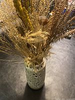 Top view of vase showing dried plant stems inside and vase's top opening, highlighting curved rim and speckled textured glaze.