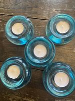 Top view showing all five blue glass holders with white tea light candles inside arranged together.