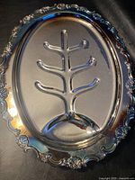 Oval silver turkey server with ornate floral border and central raised tree-branch shaped riser for holding a turkey.