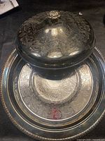 Top view of silver-plated pie serving tray with matching lid showing embossed floral and geometric patterns and flower knob.