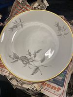 Photo of one porcelain soup bowl showing white base, black floral pattern, and gold rim.