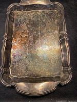 Top view of rectangular silverplate tray showing ornate embossed floral and scroll pattern with scalloped edges and integrated handles