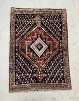 Full view of the rectangular Kurdish rug showing central light blue medallion and dark background with repeating motifs.