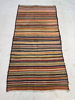 Full view of a rectangular Kilim rug laid flat on the floor showing horizontal multicolor stripes.