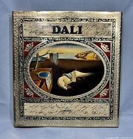 Front cover of the book showing embossed silver design with surrealist art of melting clocks by Salvador Dali and the title 'DALI'
