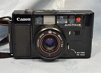 Front view of Canon AF35M camera showing lens, flash, auto focus sensor, and controls.