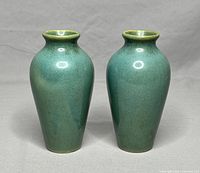 Pair of green stoneware pottery vases viewed from front showing overall shape and color.