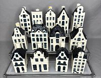 Front view of 14 vintage blue and white Delft miniature ceramic Amsterdam houses on display stand.