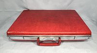 Front view of a red Jetliner hard shell briefcase with metal trim and handle, closed.