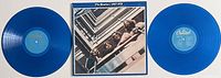 Both blue vinyl discs of The Beatles 1967-1970 album with album cover in center, displayed flat.