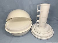 Full view of picnic set with plates, bowls, cups stacked, showing off-white color and nesting design.