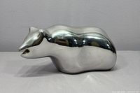 Side profile of smooth silver-toned bear sculpture on a neutral background.