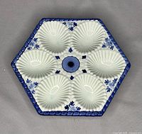 Top view of hexagonal deviled egg tray showing six shell-shaped compartments with blue decorative border and floral accents.
