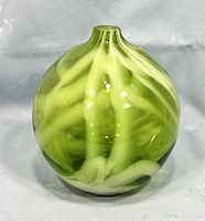 Front view of the round green and white swirled hand blown glass vase with smooth glossy surface and narrow neck top opening.