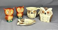 Front view of all five ceramic owl kitchenware items showing two orange owl salt and pepper shakers, one white and brown owl creamer jug, one white and brown owl napkin holder, and one small owl teabag holder.