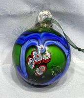 Front view of Murano glass ball ornament showing green, blue swirl, and millefiori floral design.