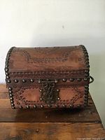 Front view of closed box showing leather exterior, stamped patterns and brass studs