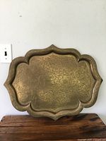 Full front view of large brass tray showing overall shape and etched floral and ornamental designs
