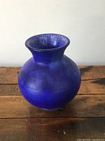 Front and side view of small cobalt blue pottery squat vase on wooden surface