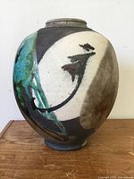 Front view of vase showing abstract design with black, white, turquoise, and brown colors