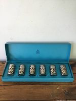 Set of six silver-plated salt and pepper shakers with cobalt liners arranged inside its original turquoise Birks box.