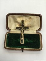 Top view of the vintage rosary cross inside the antique leather jewelry box, showing the crucifix detail and box interior with embossed lettering.
