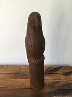 Front view of the vintage Mid Century modern carved wooden parrot sculpture on wooden surface.